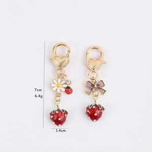 Creative strawberry keychain with red fruit, bow, and flower charm in golden finish