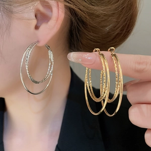 Detail of 18k gold plated three-layer hoop earrings with textured metallic finish