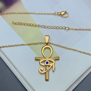 Golden Ankh Cross and Eye of Horus necklace with blue zircon on a book page