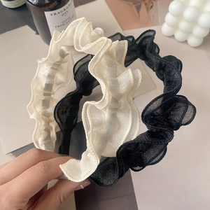 Close-up of pleated mesh headband in beige and black with ruffle fabric detail