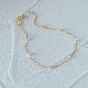 Detalle de la cadena dorada de plata S925 con perlas blancas y etiqueta grabada