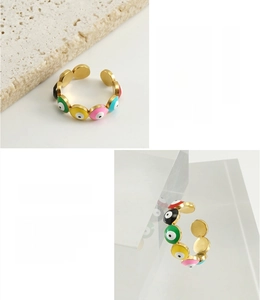 Macro detail of 18K gold plated evil eye rings showing colorful inlay and polished steel