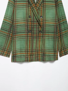 Detail eines waldgrünen zweireihigen Blazers mit Retro-Karomuster und dunklen Knöpfen