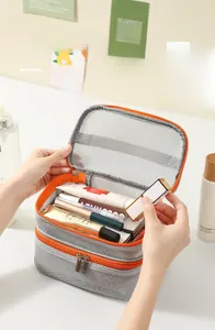 Close-up of double-layer mesh cosmetic bag featuring grey netting and orange zipper trim