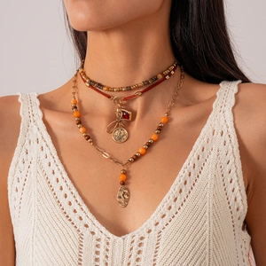 Detail of layered bohemian necklace featuring vintage coins and red gemstone pendants