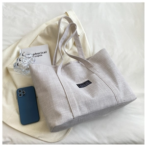 Detailed macro of beige canvas tote bag with woven texture and fashion label detail