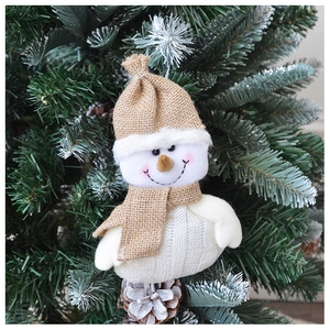 Detailed close-up of a knitted snowman ornament hanging on a festive Christmas tree branch