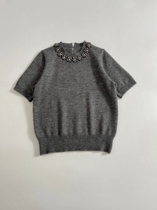 Detailed view of grey short sleeve knit top featuring a crystal floral embellished neckline