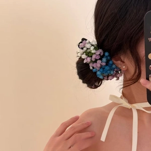 Detail view of elegant floral hair clip with white and blue petals on a messy bun hairstyle