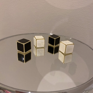 Vue détaillée de boucles d'oreilles cubes géométriques noir et blanc avec cadre doré