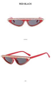 Detail of red cat-eye sunglasses with rhinestone decorations and black lenses