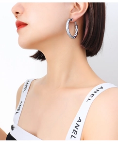 Detail view of large silver twisted hoop earring on model with high metallic luster