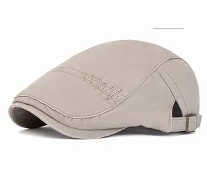 Detail of off-white cotton flat cap showing side zigzag stitching and adjustable metal buckle