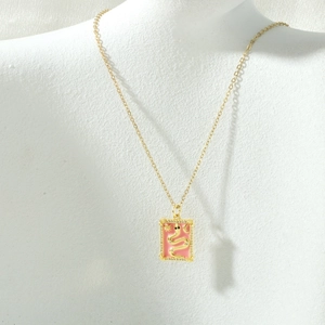 Detail of pink enamel tarot pendant with golden snake and zircon on a white mannequin