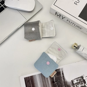 Close-up of mini denim earbud cases in light blue and dark grey with snap closure