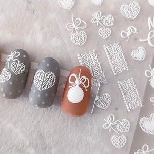 3D embossed white nail stickers with heart and bow designs on grey and red nails