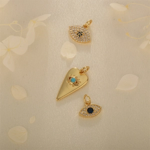 Three gold evil eye and heart pendants with blue zircons and turquoise on beige fabric
