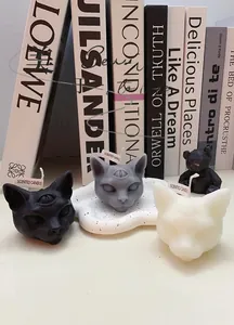 Detailed view of spooky three-eyed cat and bear scented candles on a white tray