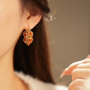 Detail view of vintage gold floral hoop earrings with brown rhinestones on a female model
