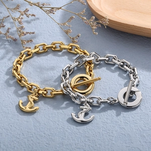Gold and silver nautical anchor bracelets with toggle clasp on wooden tray