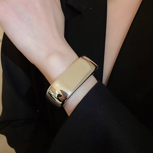 Polished silver wide wavy cuff bracelet shown on wrist with elegant black blazer sleeve