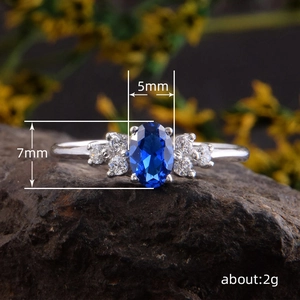 Modieuze zilveren ring met ovale blauwe edelsteen en witte zijstenen op een donkere steen