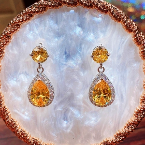 Detailed view of teardrop yellow zircon earrings with sparkling halo pave settings