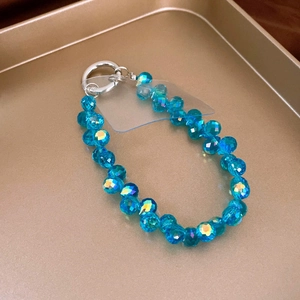 Detail shot of crystal phone strap with blue multifaceted beads on a golden tray