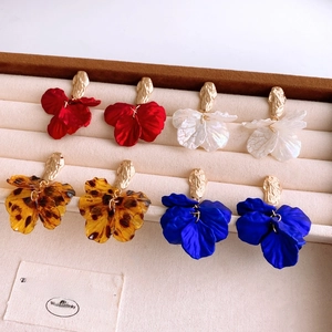 Flat lay of colorful acrylic petal earrings in red, white, amber, and blue on a tray