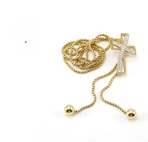 Close-up of 18K gold-plated cross pendant with sparkling rhinestones and bead chain
