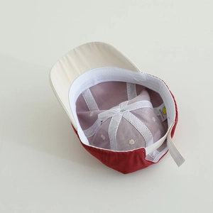 Close-up of red and beige kids baseball cap with adjustable strap and inner embroidery