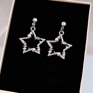 Detailed view of silver star earrings with hollow pentagram design and pearl accents