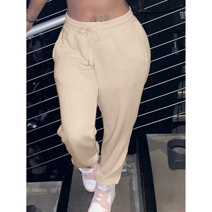 Detail view of beige joggers with drawstring waist and ribbed cuffs on stairs