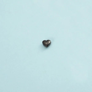 Close-up of a polished heart-shaped stainless steel pendant on a light blue background