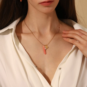Detail of 18K gold necklace with flower charm, pearl and coral pendant on model
