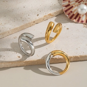 Minimalist two-tone gold and silver stainless steel rings on a marble stone base