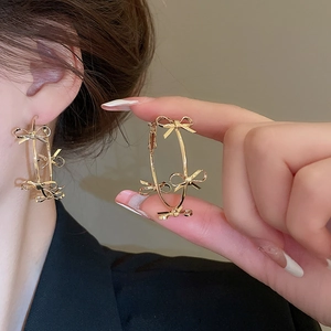 Macro detail of gold-plated hoop earrings with small decorative bows for women