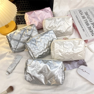 Quilted PU heart cosmetic bags in silver, white and pink on a cozy home desk setup