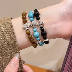 Gros plan de trois bracelets en perles avec pendentifs croix en argent vintage sur un poignet