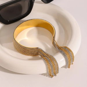 Detailed shot of a gold wide-band open cuff bracelet with layered bead chain tassels