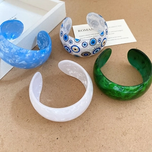 Detail of colorful acrylic open bangles with marble texture and evil eye design