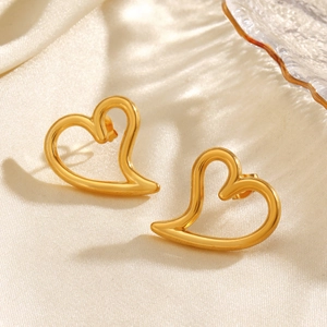 Pair of gold hollow heart stud earrings in polished stainless steel on silk background