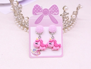Detail view of pink glitter ball earrings with a cute unicorn pendant for kids