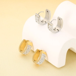 Macro detail of U-shaped hoop earrings in gold and silver with rows of zircon stones