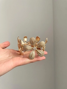 Detailed macro view of large golden flower bracelet with woven texture and crystals