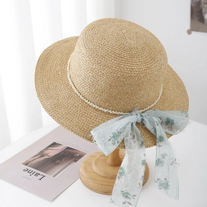 Close-up of flat top straw hat with pearl beads and blue floral chiffon ribbon detail