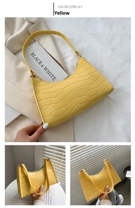 Detail of yellow crocodile embossed leather hobo bag with zip top and smooth texture