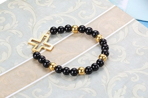 Macro view of elastic beaded bracelet with black onyx beads and golden cross charm