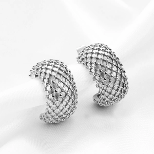 Detailed macro view of silver stainless steel C-shaped earrings with dotted grid texture