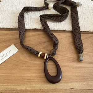 Close-up of leopard print fabric necklace with wooden beads and acrylic oval pendant